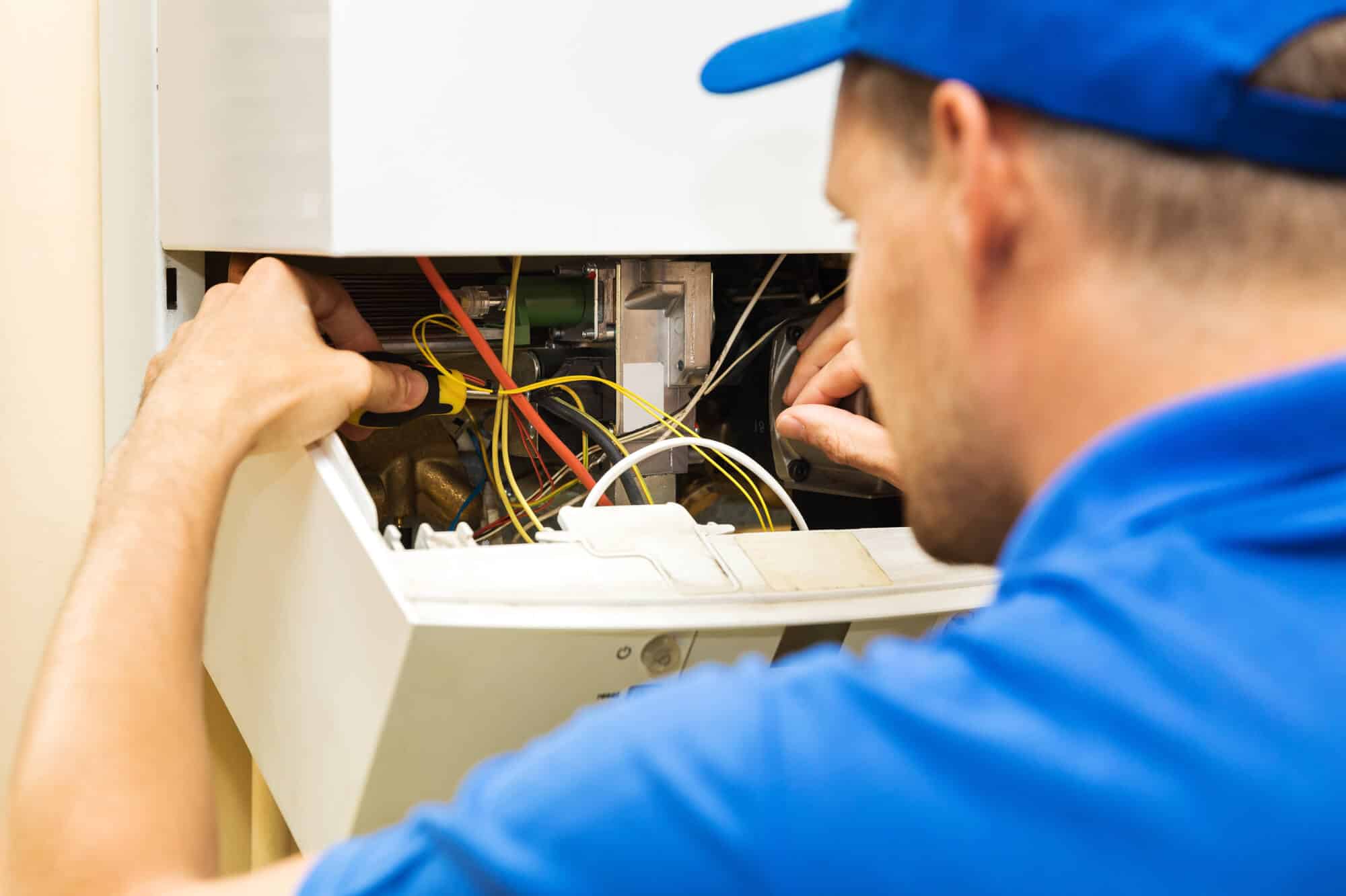 A technician checking on electrical wiring in a panel.
